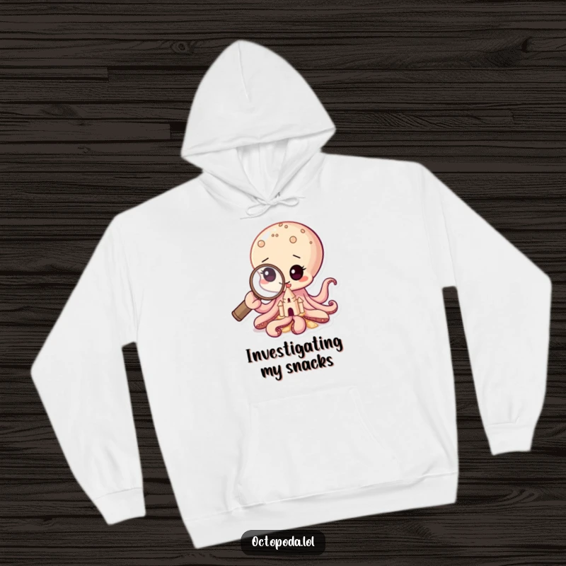 Funny hoodie featuring a baby octopus intently studying a sandcastle with a magnifying glass, representing deep thought.